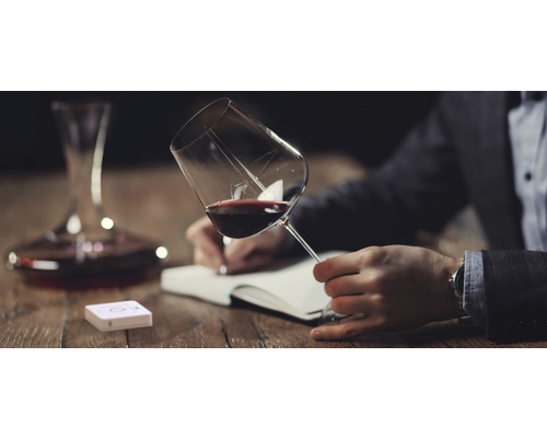 Scène avec verre à vin rouge, carafe à décanter, carnet et capteur sur une table en bois
