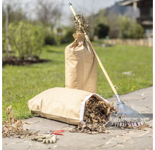 Gartenszene mit zwei Papiersäcken gefüllt mit Gartenabfällen, einem Rechen, einer Gartenschere und Gartenhandschuhen.
