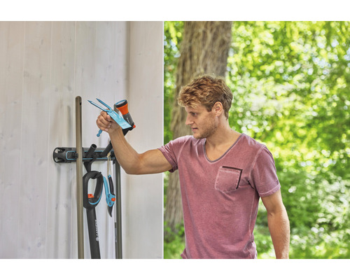 Un homme range des outils de jardin sur un support mural