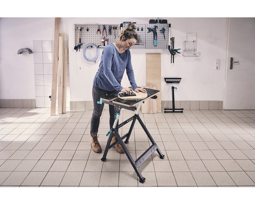 Frau arbeitet an einer Werkbank mit Werkzeug an der Wand