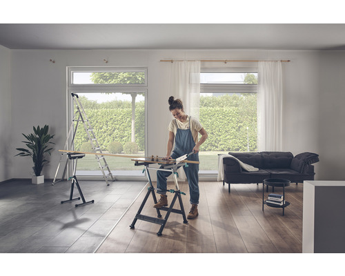 Eine Frau sägt Holz auf einer Werkbank in einem hellen Raum
