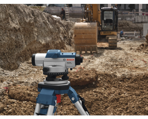 Logo Bosch. Chantier avec niveau sur trépied et excavatrice en arrière-plan.
