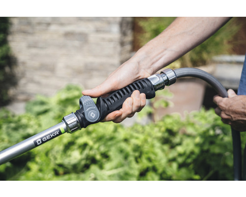 Eine Person hält eine Gartenspritze der Marke Geka an einen Gartenschlauch.