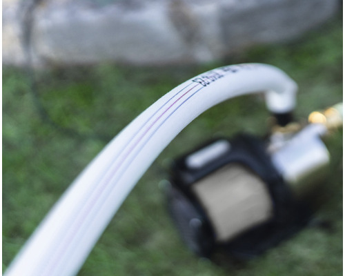 Weisser Wasserschlauch verbunden mit einer Pumpe für den Garteneinsatz