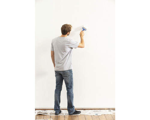 Un homme peint un mur avec un pinceau