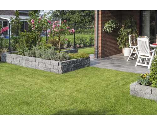 Jardin avec pelouse, parterre surélevé en pierres et terrasse avec mobilier de jardin