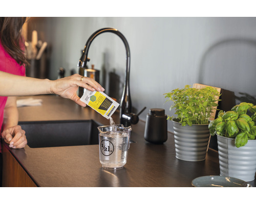 Femme versant du détergent Kärcher dans un gobelet gradué rempli d’eau.