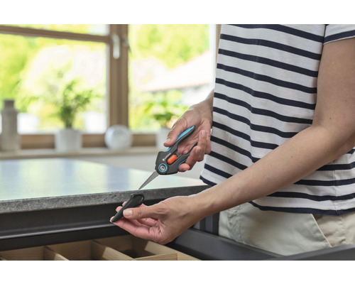 Une personne tient des ciseaux à plantes Gardena avec un capuchon de protection au-dessus d''un tiroir.