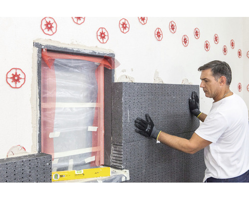 Handwerker bringt Dämmplatten an der Hauswand an