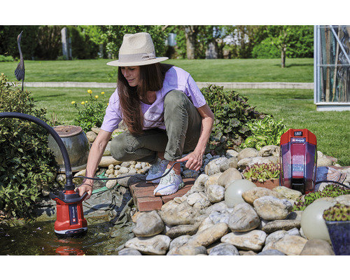 Frau bedient eine Teichpumpe in einem Gartenteich.