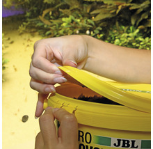 Une personne ouvre une boîte de nourriture pour poissons JBL NovoVert.