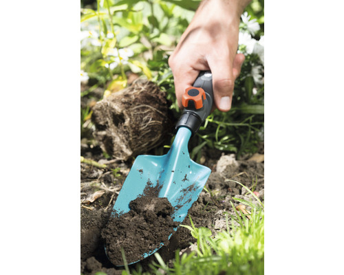 Gartenszene mit Hand und Pflanzschaufel im Erdreich