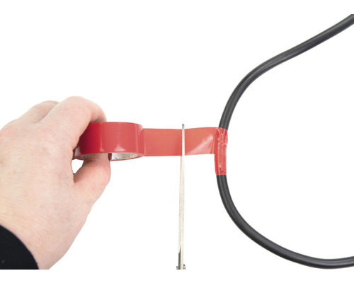 Une personne isole un câble électrique avec du ruban isolant et des ciseaux.