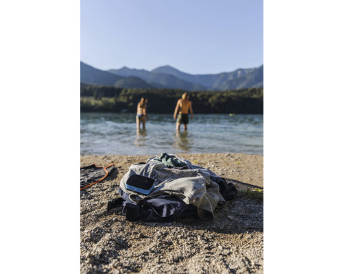 Kleiderhaufen am Strand mit Menschen im Hintergrund