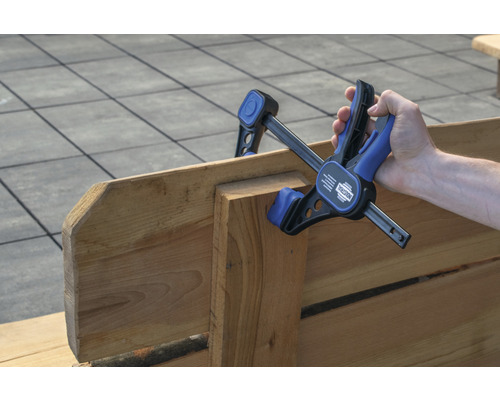 Une main fixe des pièces de bois avec une serre-joint à une main