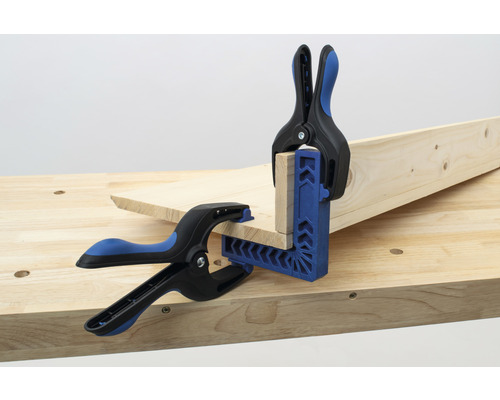 Deux pièces de bois sont fixées à un établi à l''aide d''une équerre et de serre-joints à ressort.