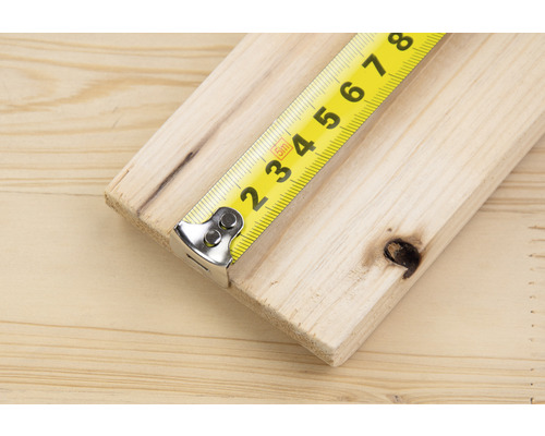 Gelbes Rollbandmaß auf einem Holzbrett