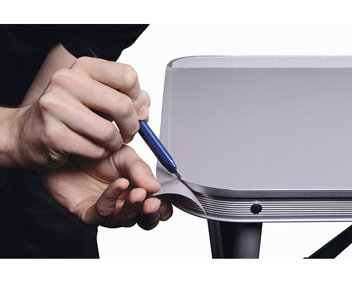 Une personne coupe un film sur une surface avec un couteau.