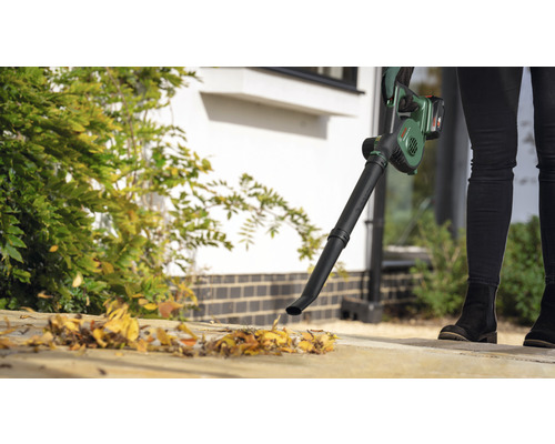 Une personne utilise un souffleur de feuilles sans fil pour jardiner.