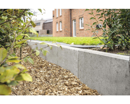 Gartenszene mit Rasenfläche, Haus und einer Betonrasenkante