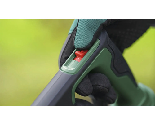 Nahaufnahme einer Hand mit Handschuh, die einen roten Schalter an einem Gartengerät bedient.