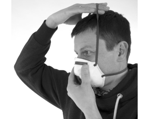 Eine Person setzt eine Atemschutzmaske auf.