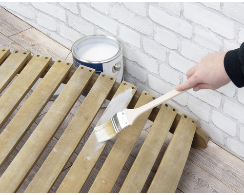 Peinture d''un sommier à lattes en bois avec un pinceau et de la peinture à côté d''une boîte de peinture