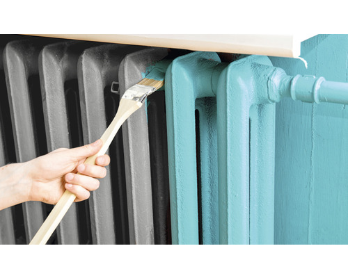 Une personne peint un radiateur avec un pinceau.