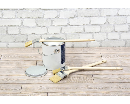 Seau de peinture avec pinceaux sur plancher en bois