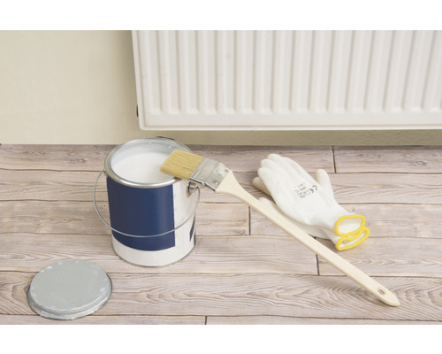 Seau de peinture avec pinceau, gants et couvercle sur plancher en bois