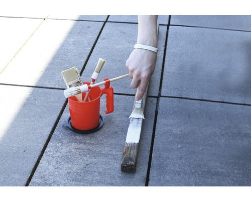 Seau de peinture avec différents pinceaux et peinture d''un morceau de bois