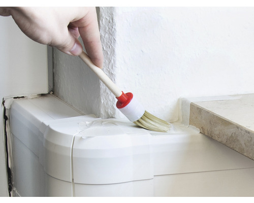 Une personne peint un coin avec un pinceau rond.