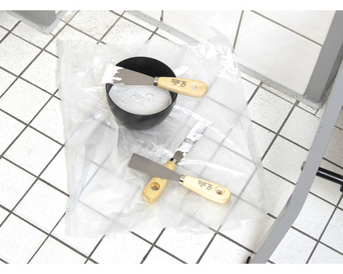 Schüssel mit Spachtelmasse und zwei Spachteln auf Folie