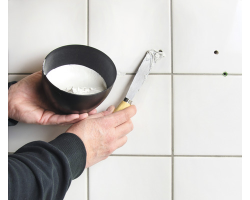 Fliesenreparatur mit Spachtel und Füllmaterial