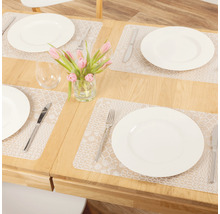 Table à manger dressée avec sets de table, assiettes, couverts, verres et vase de fleurs