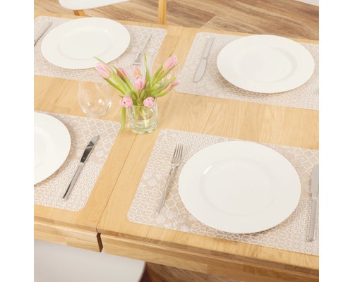Table à manger dressée avec sets de table, assiettes, couverts, verres et vase de fleurs