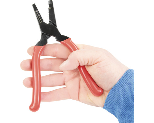 Une main tient une pince à dénuder avec des poignées rouges.