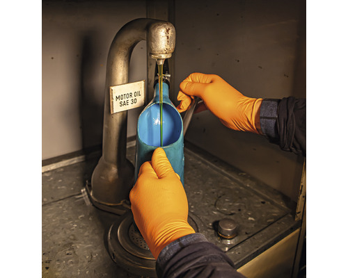 Eine Person in Handschuhen füllt Motoröl SAE 30 in einen Behälter.