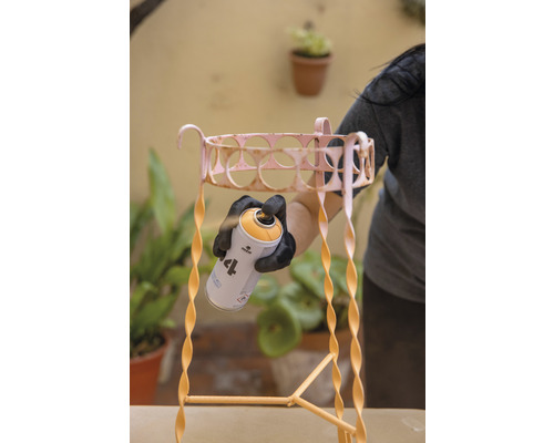 MTN Montana 94 Sprühlack Metallic Copper 400 ml Eine Person sprüht eine Metallpflanzentreppe mit einer Sprühfarbe. Die Pflanzentreppe hat ein spiralförmiges Design.