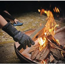 Person mit Handschuhen legt Holz in eine Feuerschale