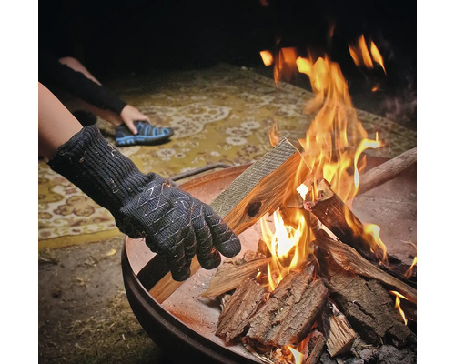 Personne avec des gants ajoutant du bois dans un braséro
