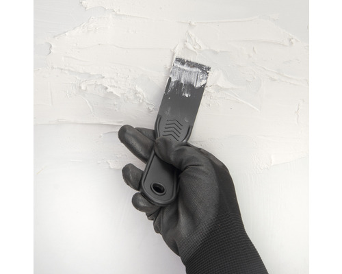 Main gantée avec spatule enduisant un mur