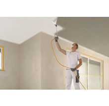 Un homme utilise un pistolet à peinture pour peindre un plafond lors de la rénovation d''une pièce.