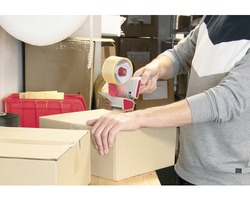 Une personne ferme un carton avec un dévidoir manuel.