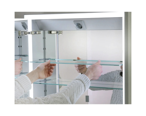 Armoire encastrable avec miroir et étagères en verre posées par des mains