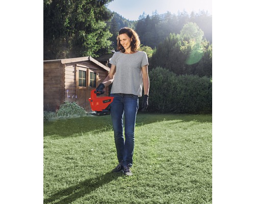 Frau benutzt eine elektrische Grasschere im Garten.