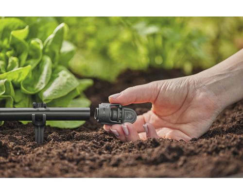 Gros plan d''une personne fixant un connecteur à un système d''irrigation dans le jardin