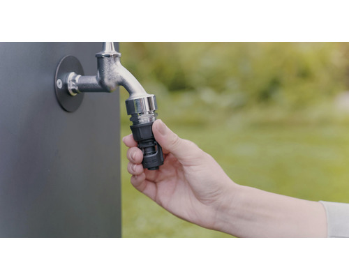 Une main fixe un raccord de tuyau à un robinet pour l''arrosage du jardin.