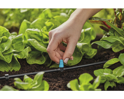 Gros plan d''une personne fixant un goutteur à un système d''irrigation dans le potager