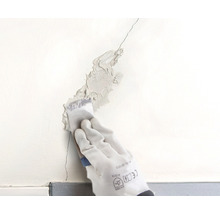 Une fissure dans un mur est colmatée avec une spatule.